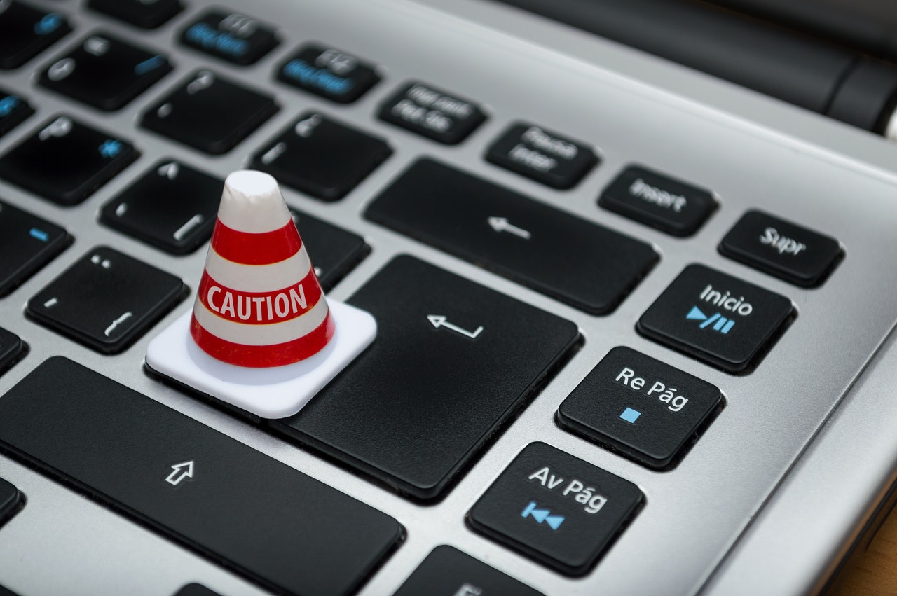 Capa de post contendo um cone branco escrito 'caution' acima de um teclado de notebook